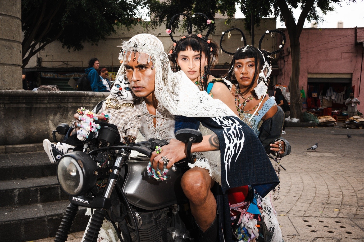 Tres modelos con trenzas, encajes y joyería posan sobre una motocicleta en La Merced.